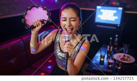 一位女士獨自興致勃勃地唱卡拉OK。 134257725