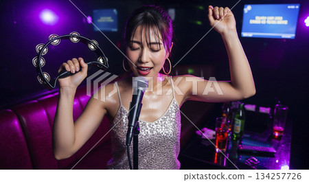 一位女士獨自興致勃勃地唱卡拉OK。 134257726