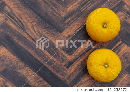 Two yuzu on a wood grain background 134258372