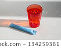 Single serving drink mix sachet next to glass, for instant beverage preparation. 134259361