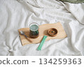 Healthy green drink and supplement capsule on small wooden tray on white blanket. 134259363