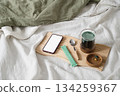 Smartphone, green superfood drink and vitamins on wooden tray in bed. 134259367