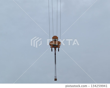 minimalist construction equipment depiction, suspended crane hook with cable in overcast outdoor 134259941