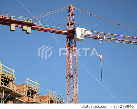 construction crane action, lifting operations underway under clear blue sky at bustling building construction crane action, lifting operations underway under clear blue sky at bustling building 134259949