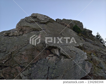 challenging rocky peak reaching skyward, summit cliff with jagged rocks and exposed surfaces challenging rocky peak reaching skyward, summit cliff with jagged rocks and exposed surfaces 134260344