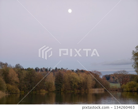 calm night scene, serene rural setting with gentle moon rising over quiet autumnal woodland shoreline calm night scene, serene rural setting with gentle moon rising over quiet autumnal woodland shoreline 134260463