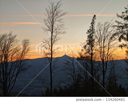 mountain dusk scene, dramatic mountain profile against pastel sunset with drifting contrails and trees mountain dusk scene, dramatic mountain profile against pastel sunset with drifting contrails and trees 134260481