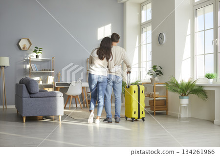 View from behind of hugging loving couple standing with suitcase at home 134261966