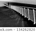 Silhouette of a lone man walking beside a curved railing in grayscale urban street scene 134262820