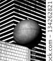 Sphere on pedestal before striped modern building in a bold black and white city scene 134262821