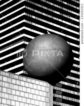 Sphere on pedestal before striped modern building in a bold black and white city scene 134262821