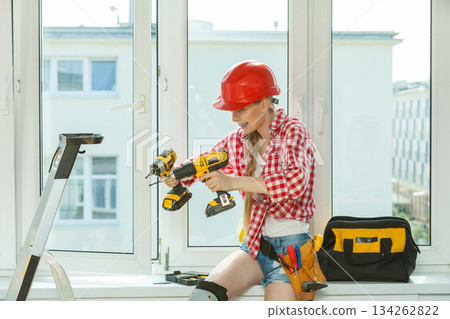 Woman using drill on window 134262822