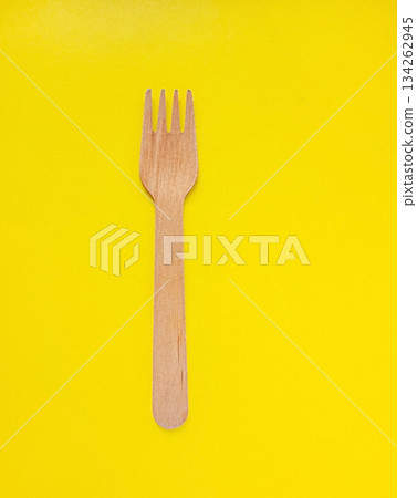 Organic bamboo disposable fork on yellow background. Environmentally friendly wooden fork. Ecology, zero waste concept with copy space. 134262945