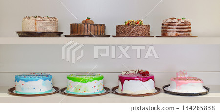 A row of cakes on a shelf, with one cake being pink A row of cakes on a shelf, with one cake being pink 134265838