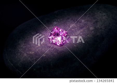 A small pink diamond is sitting on a rock 134265841