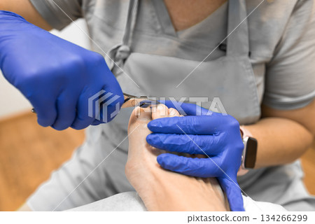 pedicure master uses nail clippers during a pedicure in a beauty salon for 55 year old woman. pedicure master uses nail clippers during a pedicure in a beauty salon for 55 year old woman. 134266299
