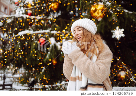 Beautiful woman playing with snow on winter street. Fashion young woman in the winter park. 134266789