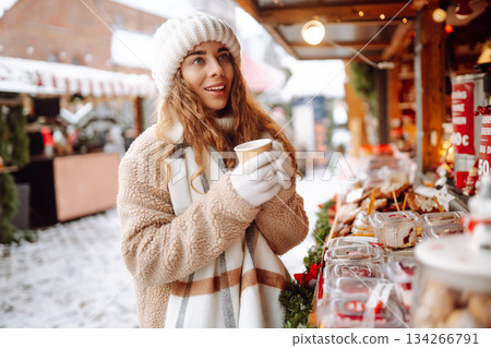 Beautiful woman playing with snow on winter street. Fashion young woman in the winter park. 134266791
