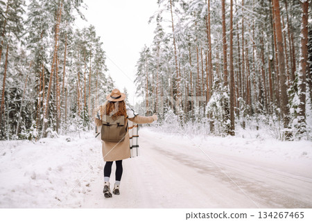 Beautiful young woman in winter forest is waiting for a car. Hitchhiking in winter. Great snowy day. Beautiful young woman in winter forest is waiting for a car. Hitchhiking in winter. Great snowy day. 134267465