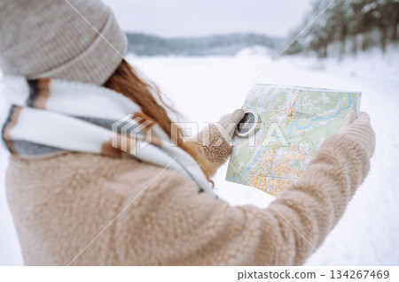 Beautiful woman traveler holds a compass and map in hands. Enjoying winter travel. Active lifestyle. Beautiful woman traveler holds a compass and map in hands. Enjoying winter travel. Active lifestyle. 134267469