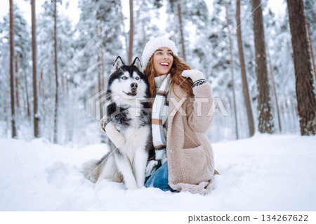 Cute woman spends time with her husky dog in the winter snowy forest. Lifestyle. Cute woman spends time with her husky dog in the winter snowy forest. Lifestyle. 134267622