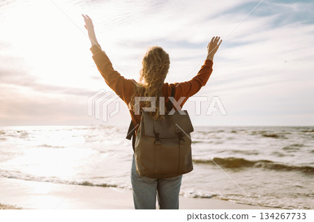 Woman enjoying breezy day near vibrant red lighthouse at sunset. Travel, weekend, lifestyle concept. Woman enjoying breezy day near vibrant red lighthouse at sunset. Travel, weekend, lifestyle concept. 134267733