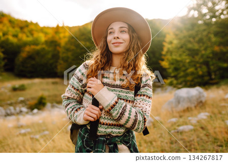 Young woman enjoys sunny afternoon in mountains while sitting on rocks. Tourism. Active lifestyle. Young woman enjoys sunny afternoon in mountains while sitting on rocks. Tourism. Active lifestyle. 134267817