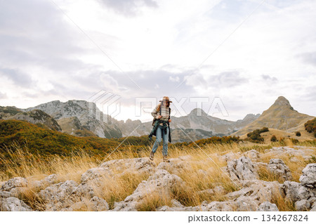Young woman enjoys sunny afternoon in mountains while sitting on rocks. Tourism. Active lifestyle. Young woman enjoys sunny afternoon in mountains while sitting on rocks. Tourism. Active lifestyle. 134267824