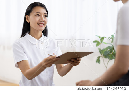 A woman in a white coat handing over documents with a smile A woman in a white coat handing over documents with a smile 134267910