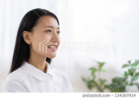 A woman in a white coat smiling by the window A woman in a white coat smiling by the window 134267914