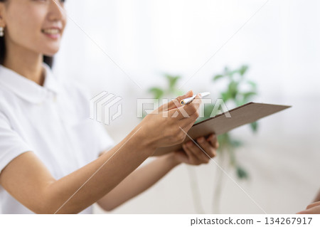Close-up of a binder and pen held by a woman in a white coat Close-up of a binder and pen held by a woman in a white coat 134267917