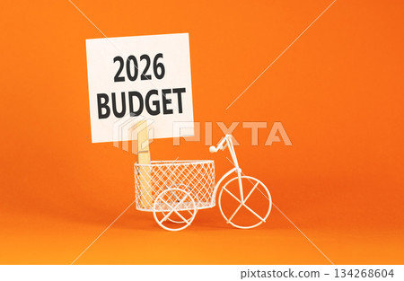 2026 Budget symbol. Concept words 2026 Budget on beautiful white paper on wooden clothespin. Beautiful orange background. Beautiful miniature bicycle. Business and 2026 budget concept. Copy space. 2026 Budget symbol. Concept words 2026 Budget on beautiful white paper on wooden clothespin. Beautiful orange background. Beautiful miniature bicycle. Business and 2026 budget concept. Copy space. 134268604