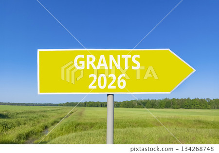 Grants 2026 symbol. Concept words Grants 2026 on beautiful yellow road sign. Beautiful green grass field forest and blue sky background. Business and grants 2026 concept. Copy space. 134268748