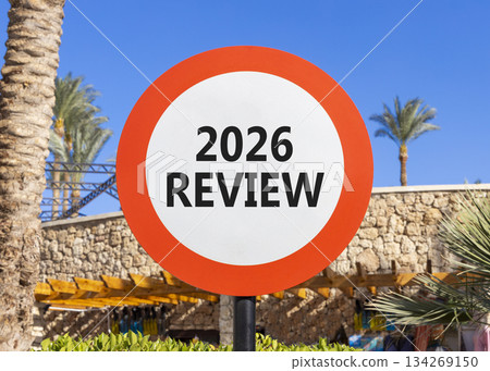 2026 Review symbol. Concept words 2026 Review on beautiful white and red road sign. Beautiful palm trees palm-trees and blue sky background. Business and 2026 review concept. Copy space. 2026 Review symbol. Concept words 2026 Review on beautiful white and red road sign. Beautiful palm trees palm-trees and blue sky background. Business and 2026 review concept. Copy space. 134269150