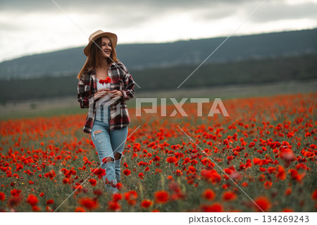 Woman walking poppy field holds flowers enjoys freedom copy space 134269243