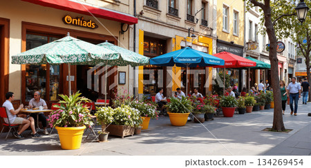 Vibrant Cafe Terrace with Colorful Umbrellas An outdoor seating area lined with tables under bright, patterned umbrellas, offering a view 134269454