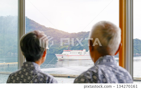 An elderly couple looking out the window at the ferry and the island 134270161