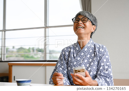 Senior woman in yukata laughs at smartphone Senior woman in yukata laughs at smartphone 134270165