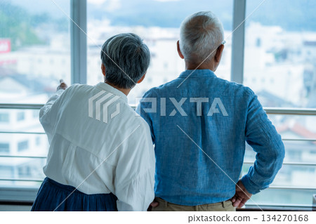 Back view of an elderly couple looking out the window Back view of an elderly couple looking out the window 134270168