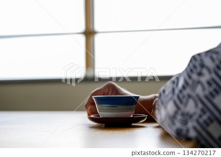 Hands holding a teacup in a Japanese-style room 134270217