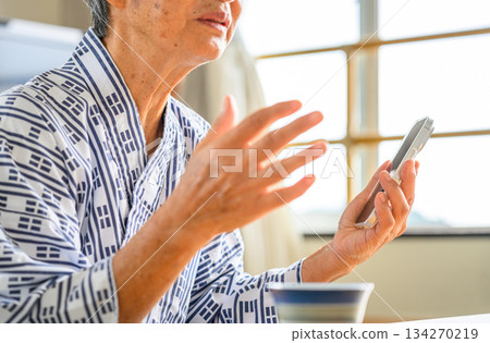 An elderly person in a yukata talking on a smartphone An elderly person in a yukata talking on a smartphone 134270219