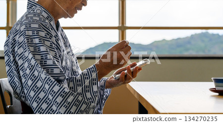 身穿浴衣的老人在室內使用智慧型手機 134270235