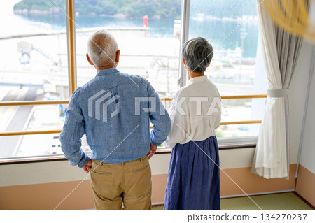 一對老年夫婦從窗戶眺望大海。 134270237