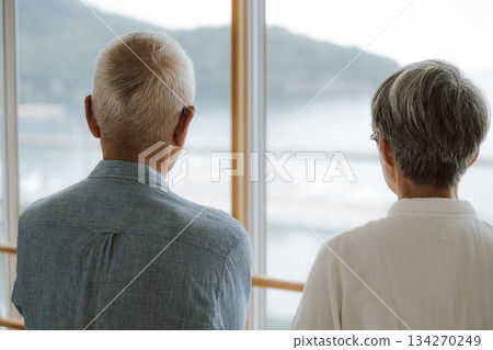 一對老年夫婦背對著鏡頭，望著窗外的大海。 134270249