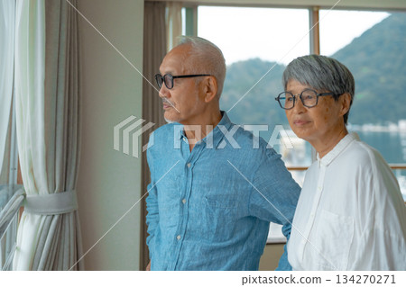 Senior couple looking out the window 134270271
