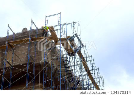 Workers on scaffolding repair building in construction area 134270314