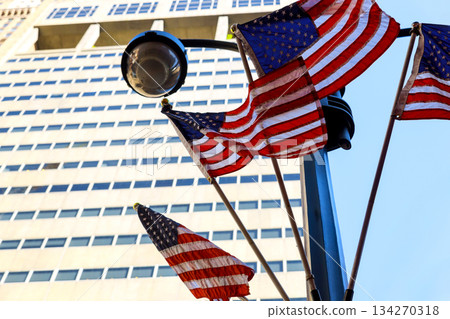 American flags wave on pole in New York city with tall buildings 134270318