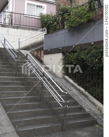 A view of a slope with concrete stairs, handrails and a bicycle ramp in a residential area A view of a slope with concrete stairs, handrails and a bicycle ramp in a residential area 134270382