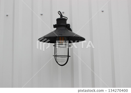 Fisherman Style Outdoor Light Stock Image. Vintage Outdoor Lantern with Black Cap On a White Wall Fisherman Style Outdoor Light Stock Image. Vintage Outdoor Lantern with Black Cap On a White Wall 134270400