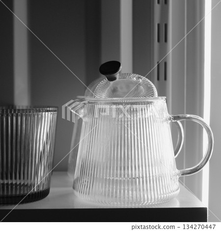Traditional glass teacup and teapots with chrome handles in the night kitchen. Clean glass kitchenware for evening tea square stock photo Traditional glass teacup and teapots with chrome handles in the night kitchen. Clean glass kitchenware for evening tea square stock photo 134270447
